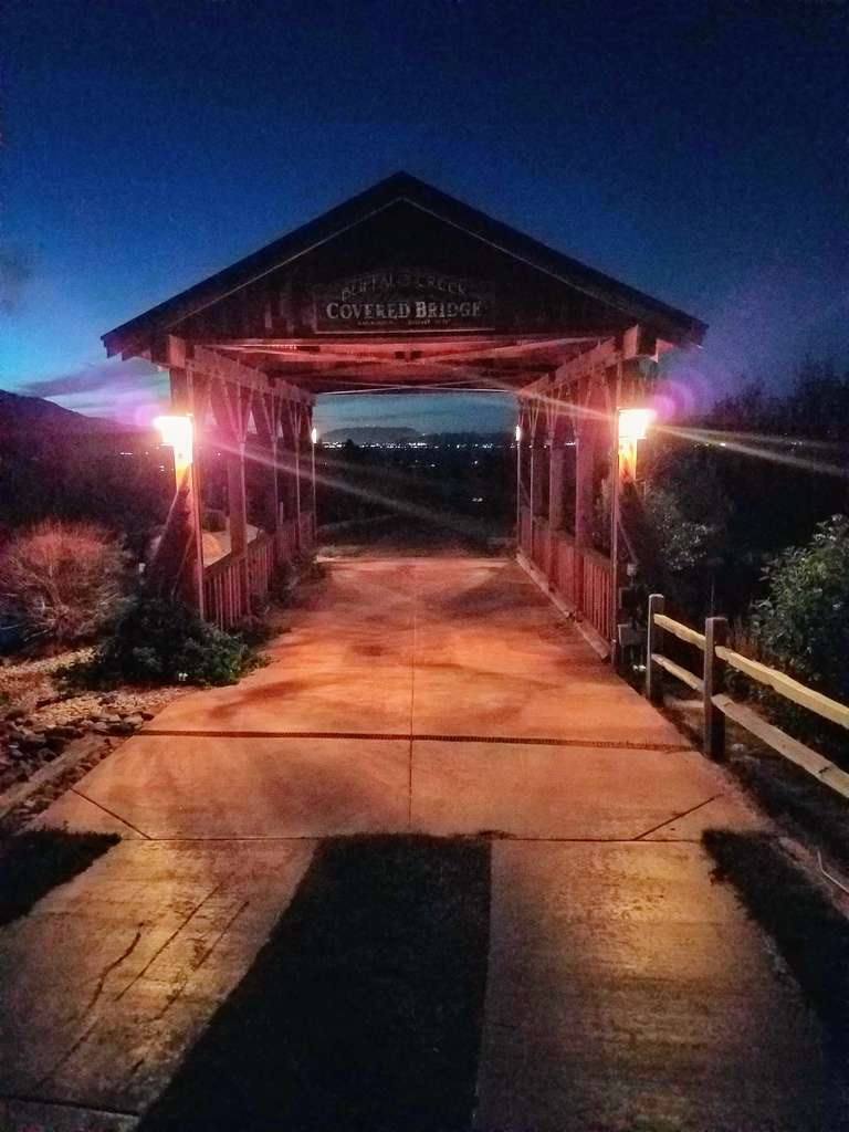 The twilight sky silhouettes the covered bridge and its night lanterns.