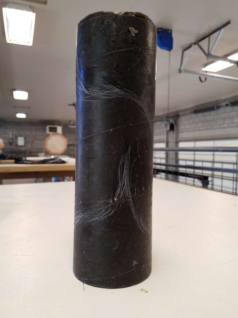 A brown, 13" high wax cylinder with first-draft design lines faintly sketched on the surface. Cast glass Stage One.
