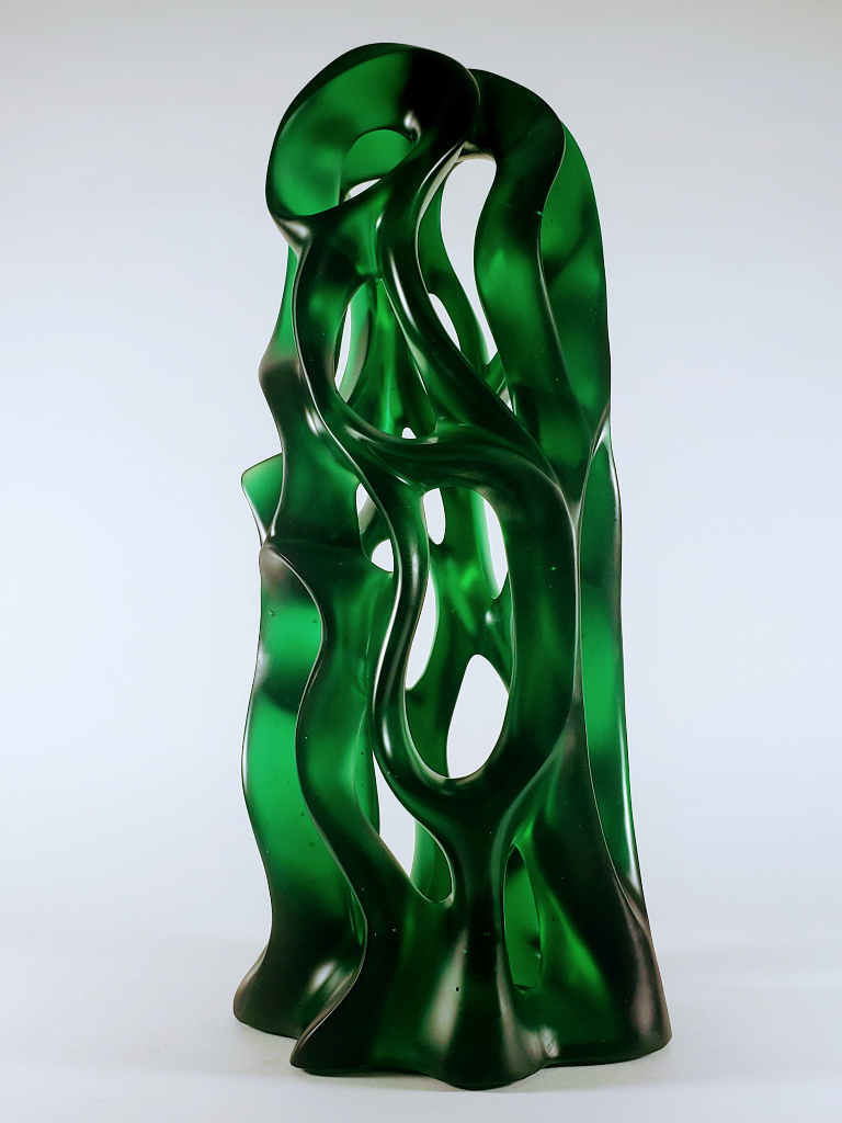 Intriguing, elongated curves create negative spaces that in turn capture light and dark shades of emerald green cast glass in the 2'-0" high Harry Pollitt sculpture.